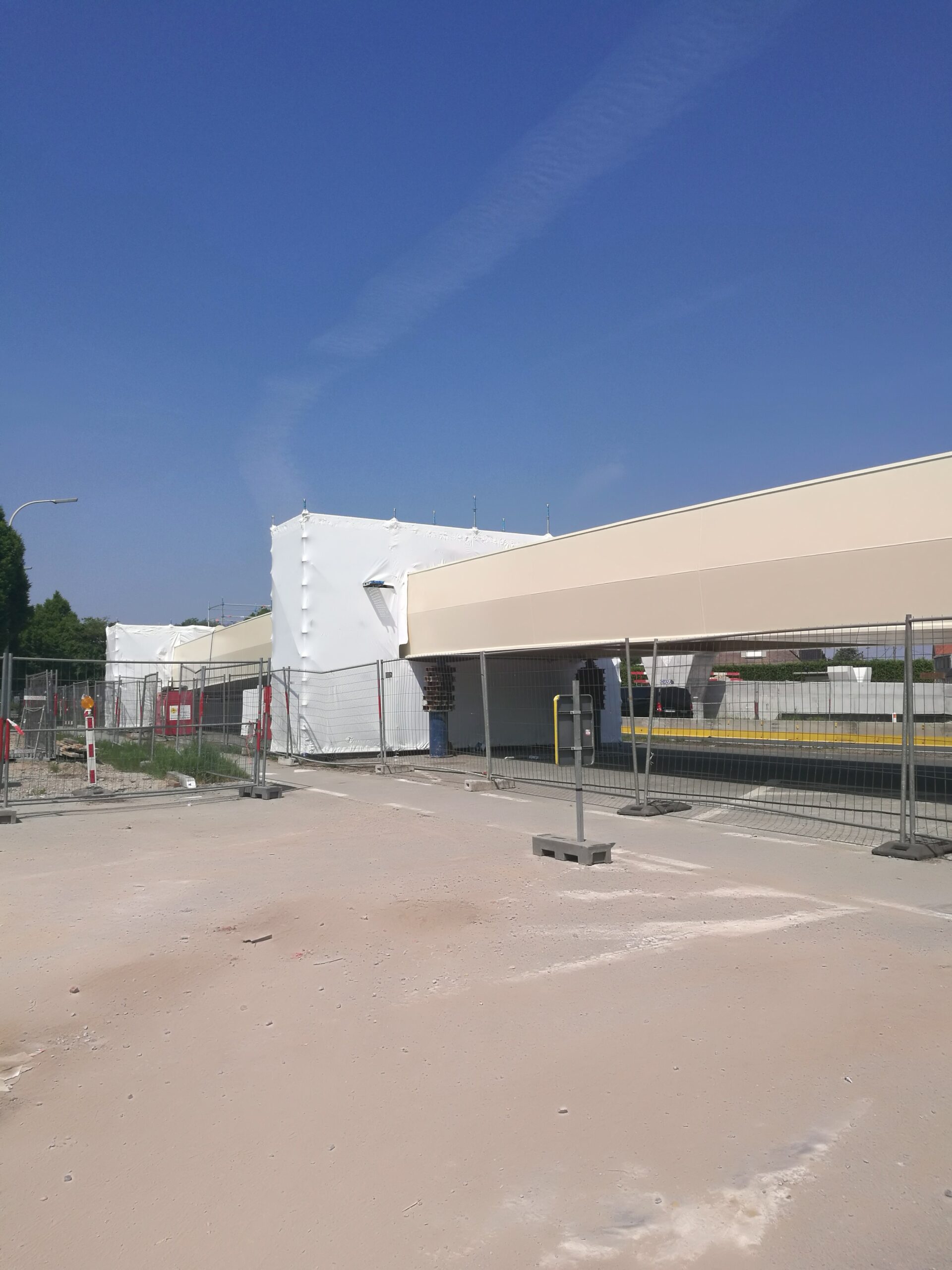 Werf met witte asbest-inpakking en veiligheidshekken tijdens actieve sanering